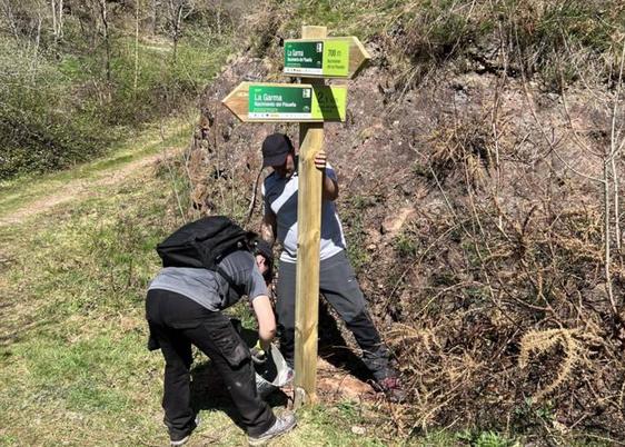 Dos operarios colocan uno de los paneles informativos de las rutas.