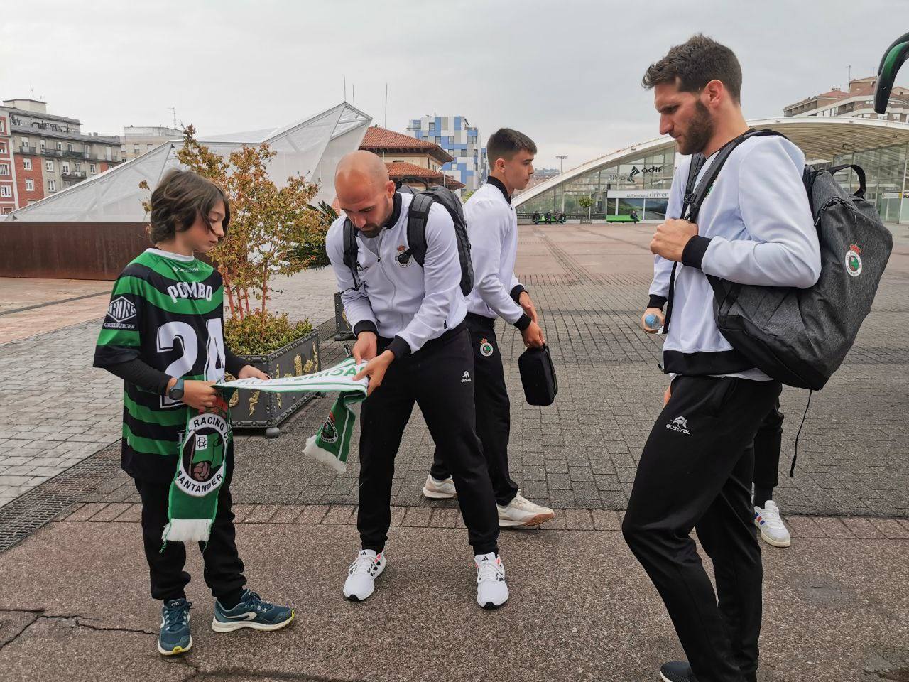 Jugadores del Racing firmando autógrafos a un joven aficionado