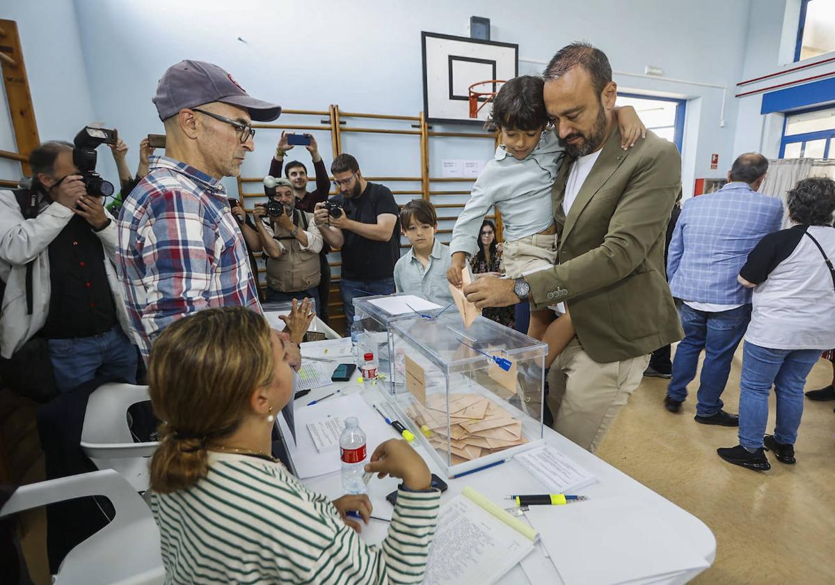 El regionalista Javier López Estrada deposita su voto con ayuda de su hijo, el pasado domingo, en Torrelavega.