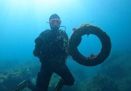 Un buceador posa con uno de los neumáticos encontrados en el fondo del mar