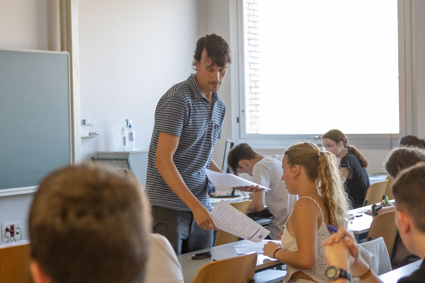 El profesor encargado del aula reparte los exámenes de Historia de España en la Facultad de Ciencias Económicas y Empresariales.