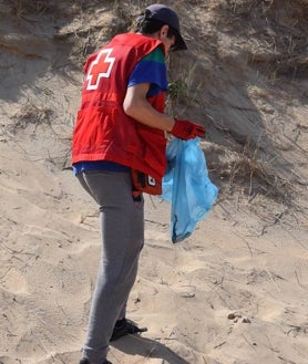 Imagen secundaria 2 - Arriba los voluntarios escuchan al coordinador de Cruz Roja y técnico ambiental Javier Cacho, al que se le puede ver debajo portando una bolsa de basura, y sobre estas líneas un voluntario en acción detectando residuos. 