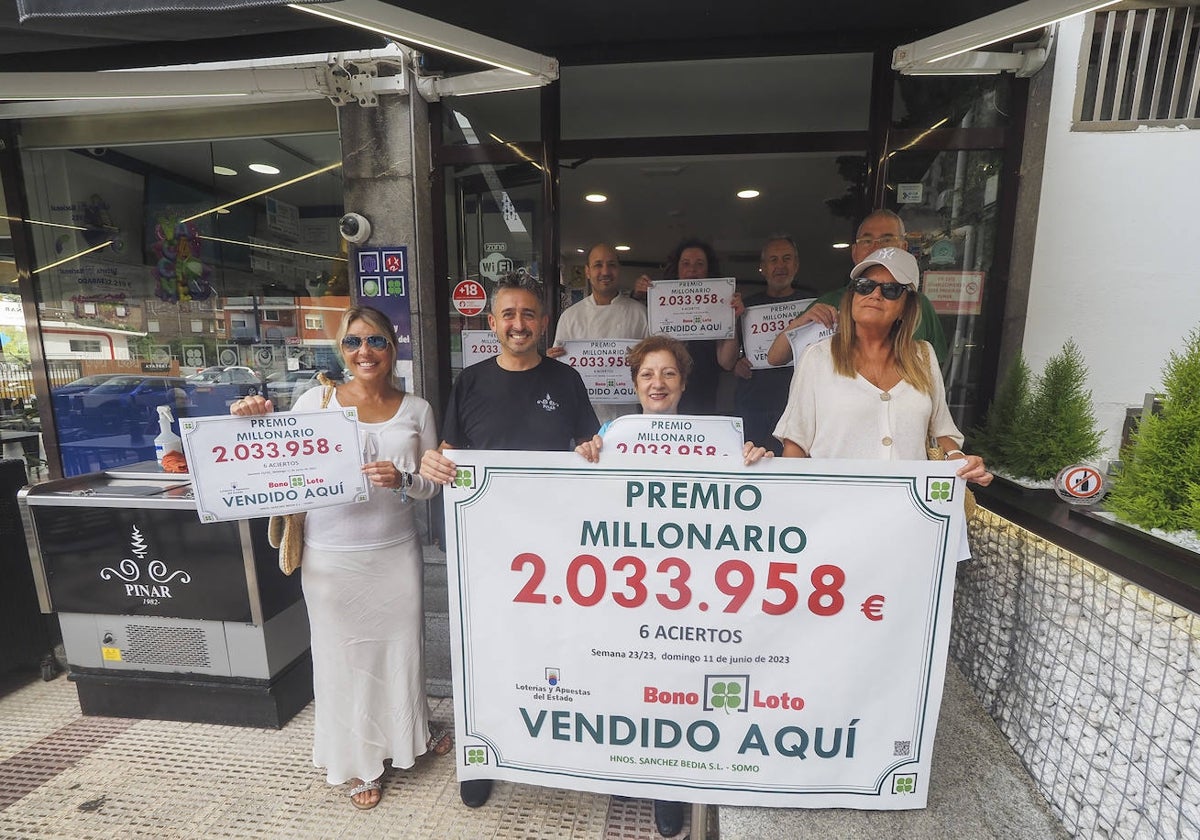 Propietarios y empleados con el cartel anunciador del premio en las puertas del establecimiento.