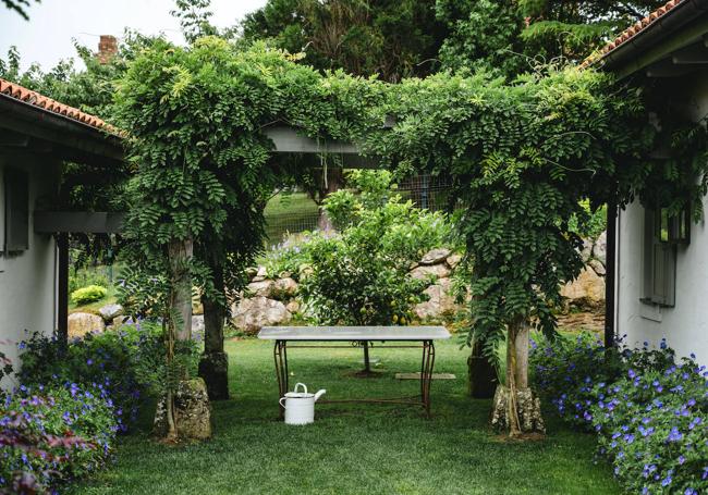 Una pérgola de madera, cubierta de glicinia, une la casa principal con la de invitados.