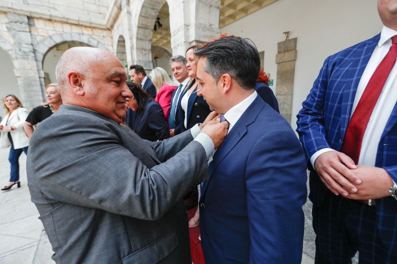 El jefe de Protocolo del Parlamento, Miguel del Río, ajusta la corbata al diputado del PP Carlos Caramés.