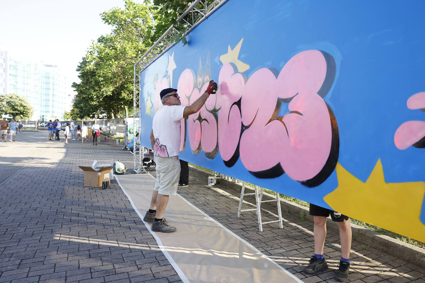 Un grafitero retoca el logo del festival en 'fan zone' del Myfest, instalada frente a los Campos de Sport de El Sardinero. 