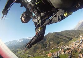 Un parapentista volando sobre Potes con los Picos de Europa al fondo.