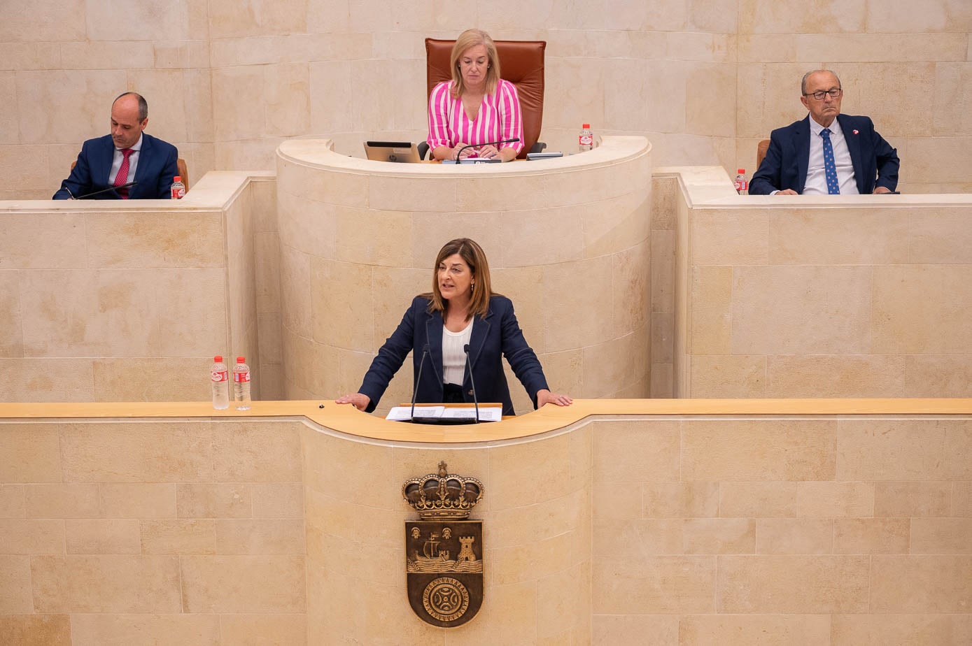 Marís José Sáen de Buruaga durante su intervención. Detrás de ella, la presidenta del Parlamento, María José González Revuelta, flanqueada por Javier López Marcano y Juan José Alonso Venero.