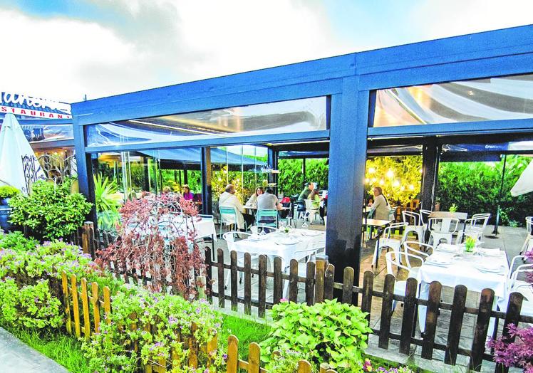 La terraza de este establecimiento se rodea de plantas y cálida iluminación.