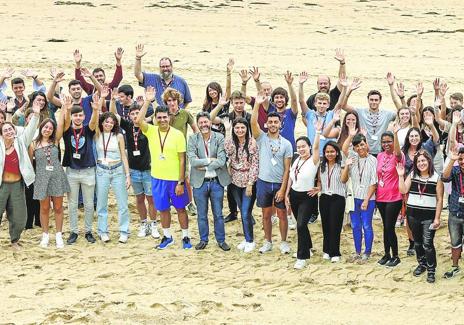 Imagen secundaria 1 - Alumnos y profesores saludan desde la playa. A la derecga, los alumnos en clase, durante una ponencia.