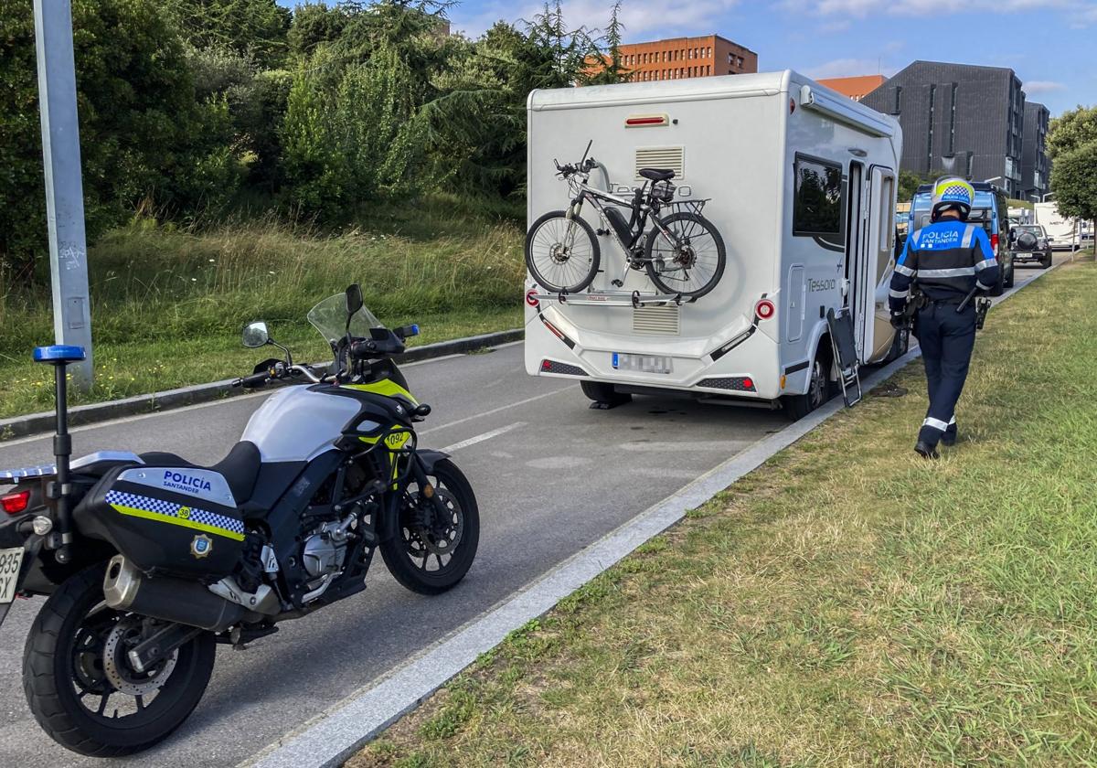 Un policía local de Santander, en el aparcamiento del parque de Las Llamas, donde avisa a los propietarios de las autocaravanas de que en esa zona no pueden acampar.