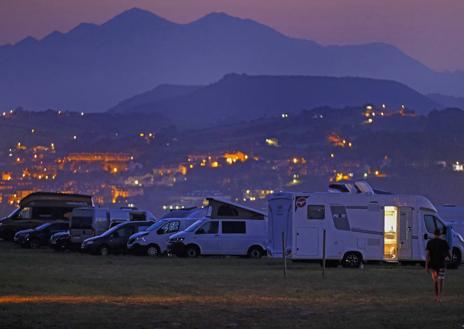 Imagen secundaria 1 - 1. Autocaravanas aparcadas en prados de Oyambre. | 2. Un grupo de usuarios sentados junto a una autocaravana en las proximidades de Las Llamas.