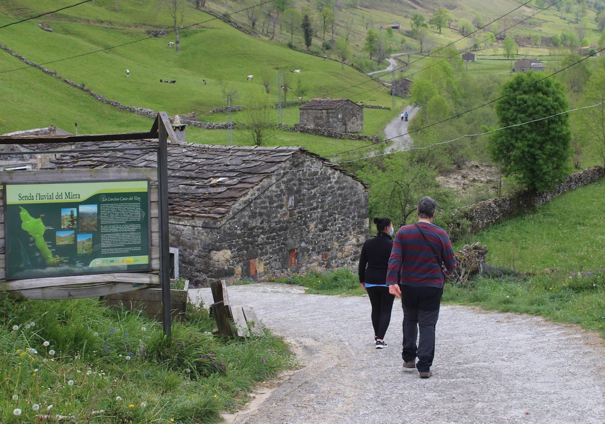 Dos senderistas pasean por la vía verde a la zona de cabañales y la Concha a los pies del puerto de Lunada.