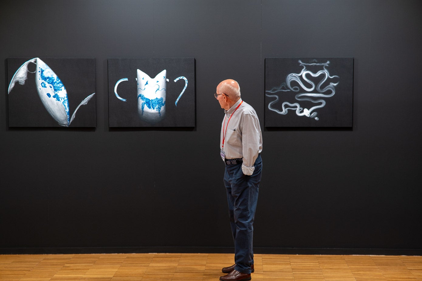 Un galerista observando tres de las obras de Artesantander.