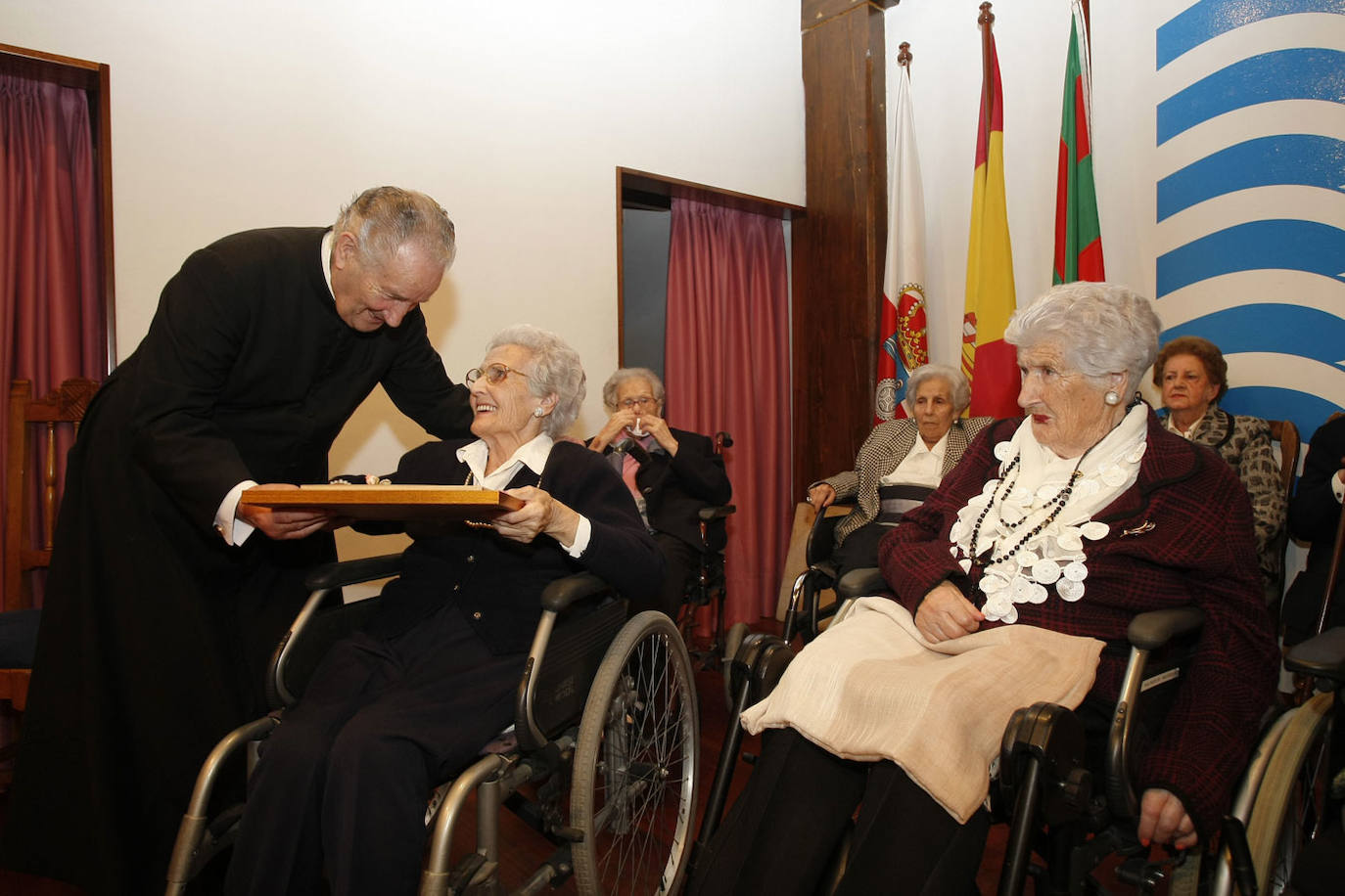 Una mujer residente en la Fundación Asilo y mayor de 90 años recibe una placa de manos de Luis López Ormazábal en 2015. 