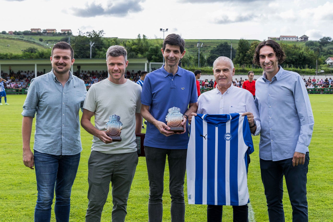 El concejal de Deportes de Astillero, Alejandro Hoz, el director deportivo del Racing, Mikel Martija, el presidente del Alavés, Alfonso Fernández de Trocóniz, el presidente de la Cultural de Guarnizo José Luis López y el alcalde de Astillero, Javier Fernández, posan con un trofeo y una camiseta conmemorativa. 