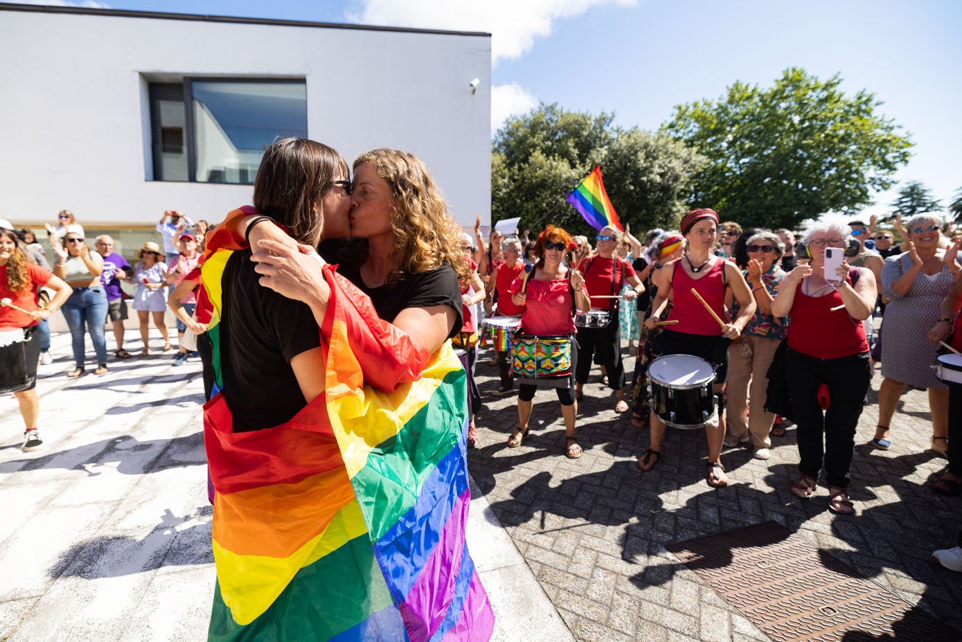 Un beso envueltas en la bandera con la que los colectivos LGTBI reivindican sus derechos en todo el mundo