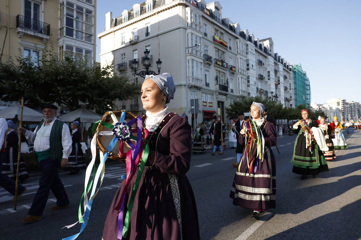 Una mujer toca la pandereta decorada con cintas de colores.