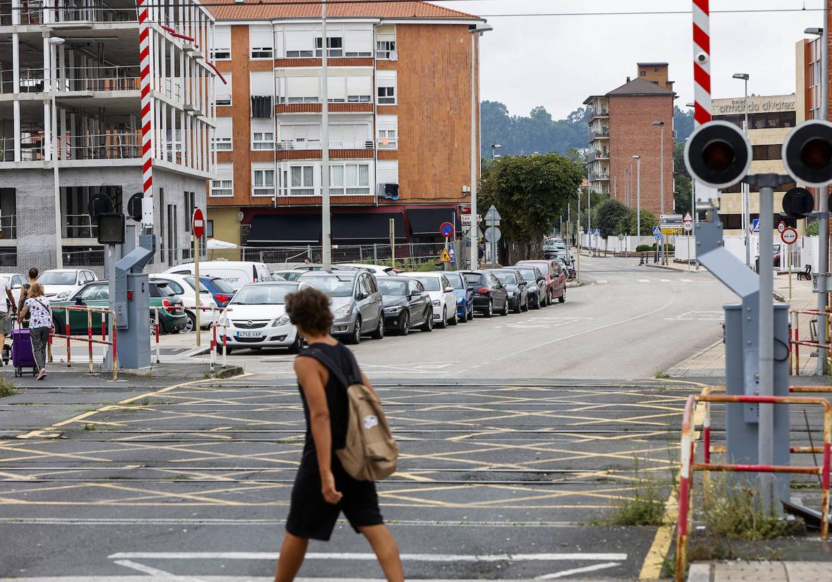 Un vecino cruza la calle Pablo Garnica, una de las vías a renovar, frente al paso a nivel ferroviario, en Torrelavega.