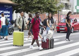 Unos turistas cruzan la carretera en el Paseo de Pereda de Santander con sus maletas.