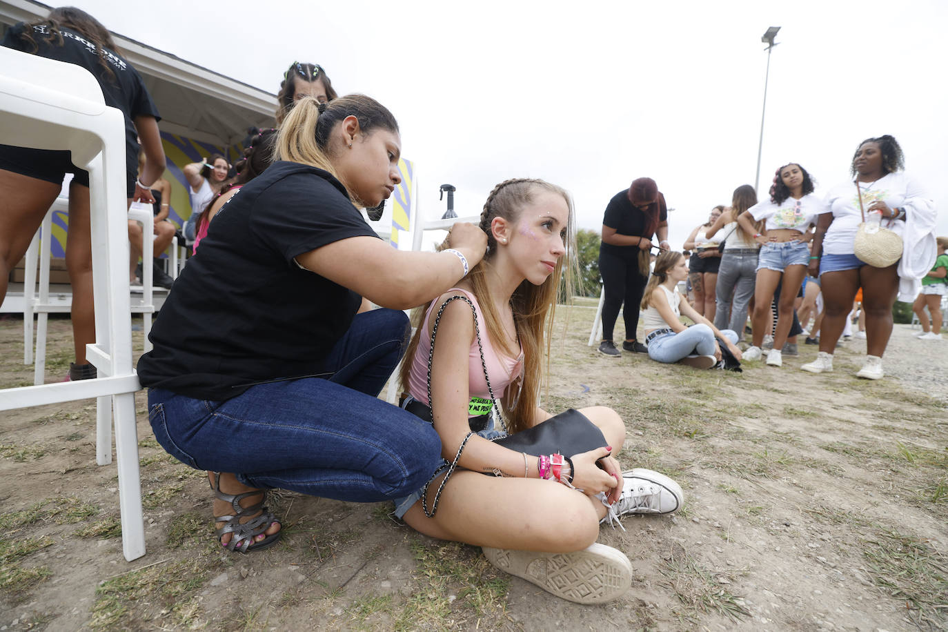 Una joven se hace unas trenzas mientras espera que arranque el concierto