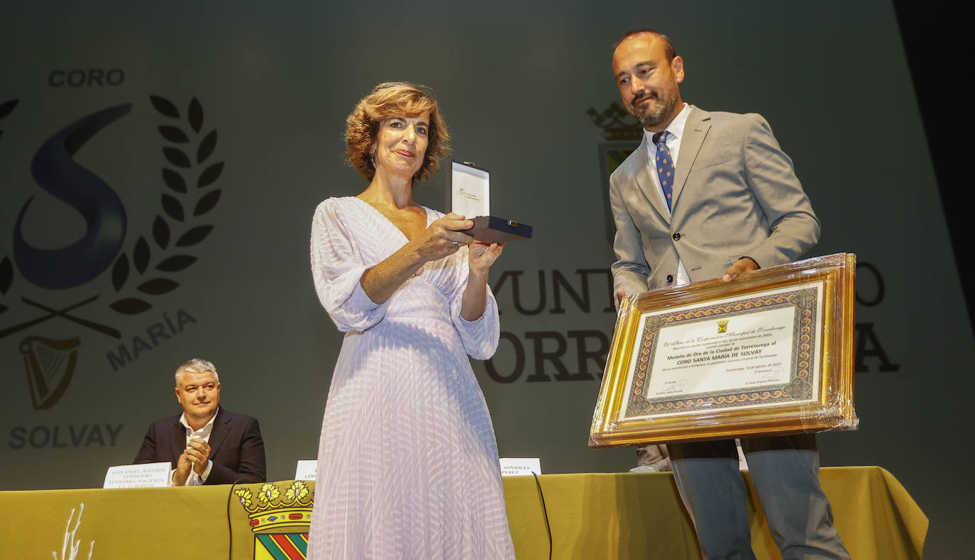 La presidenta de la entidad coral, Sonsoles Pérez, recibe la medalla de manos del alcalde, Javier López Estrada, este jueves, en el Teatro Concha Espina de Torrelavega.