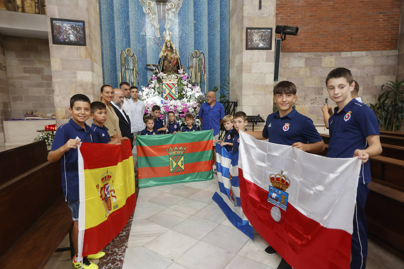 La directiva y las categorías inferiores con las banderas de España, Torrelavega, la Gimnástica y Cantabria delante de la Virgen Grande.