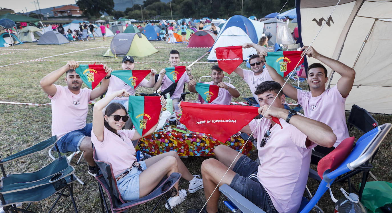 Peñistas muestran sus banderines de fiestas a la cámara, este jueves, desde su campamento en el Bulevar. 