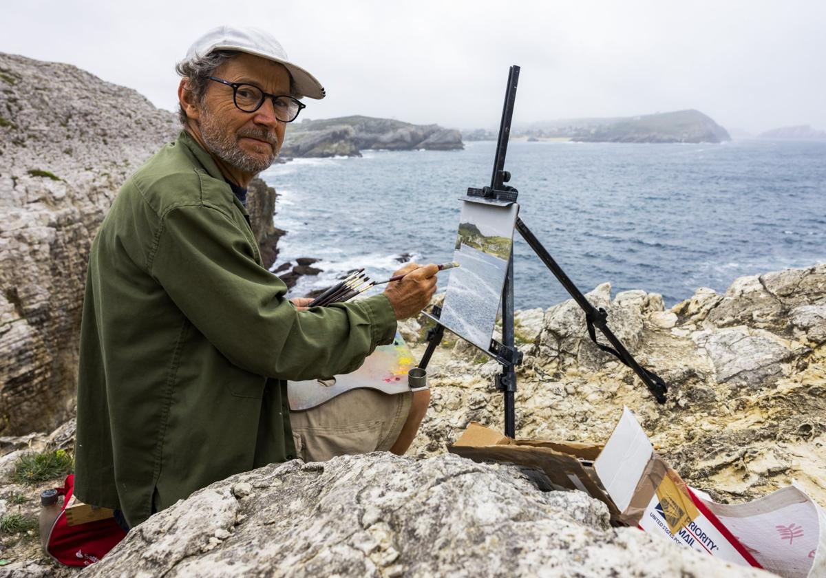 El artista Félix de la Concha pinta entre las rocas de la Virgen del Mar desde un acantilado. La obra se presenta como un puzle de 20 piezas.