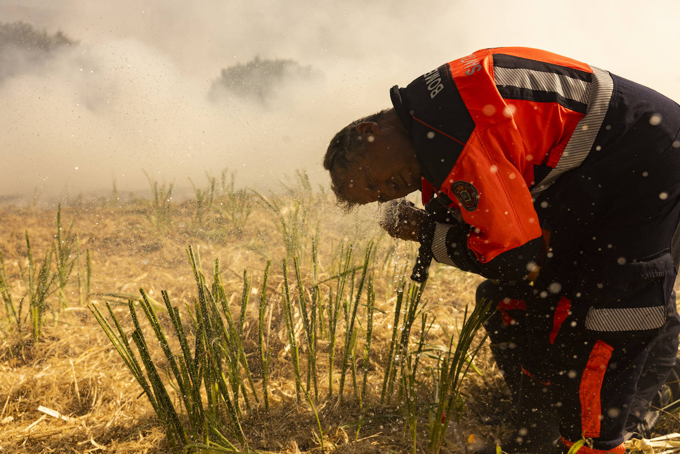 Un bombero se refresca y limpia los ojos. El humo ha sido un problema