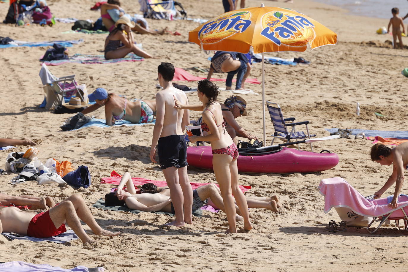 Dos jóvenes se echan crema en la playa. 