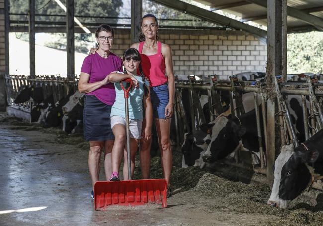 Charo Arredondo y María Gómez, con la pequeña Clara Fernández en el medio, con sus vacas en las instalaciones de La Revilla de Soba.