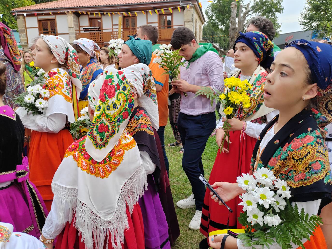 Dos jóvenes atienden lo que sucede un poco más adelante, con la ofrenda floral ya iniciada