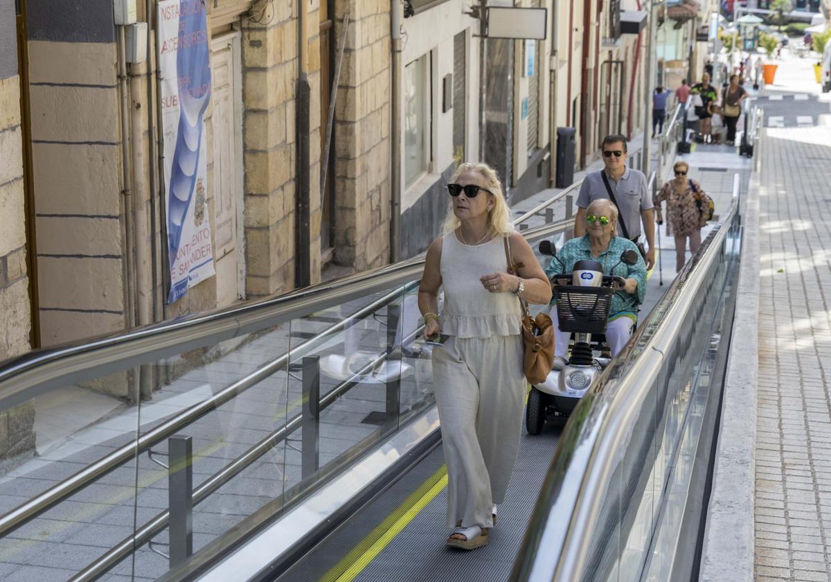 Una persona con movilidad reducida sube en la rampa mecánica.