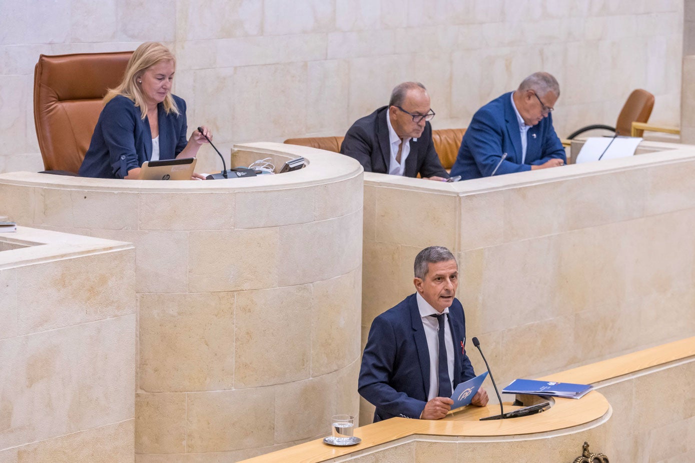 El popular Rafael de la Gándara se dirige a los diputados desde la tribuna. Sobre él, la presidenta María José González Revuelta (PP) y Javier López Marcano (PRC) y Joaquín Gómez (PSOE).