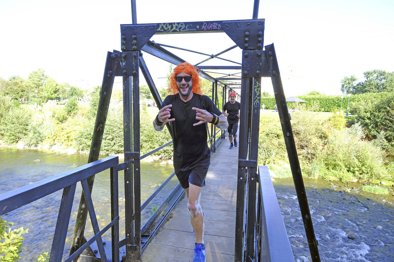 Participantes cruzan la pasarela sobre el río hacia La Viesca, en uno de los tramos del circuito.