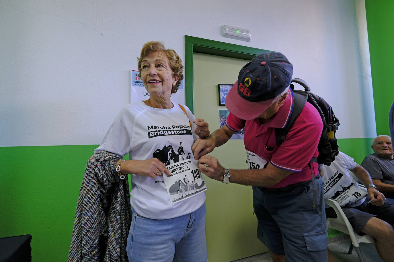 Una vecina se  coloca el dorsal para participar en la marcha, en el pabellón Vicente Trueba.