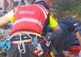 El médico, atiende a hombre antes de subirlo al helicóptero.