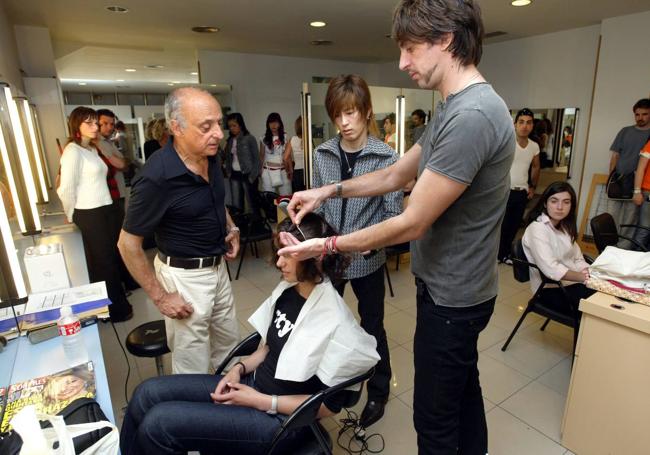 Manuel Macavi enseñando a dos jóvenes cómo cortar el pelo.