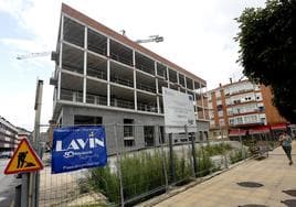 Una vecina camina por la calle Pablo Garnica de Torrelavega frente a las obras paralizadas del futuro centro de acogida.