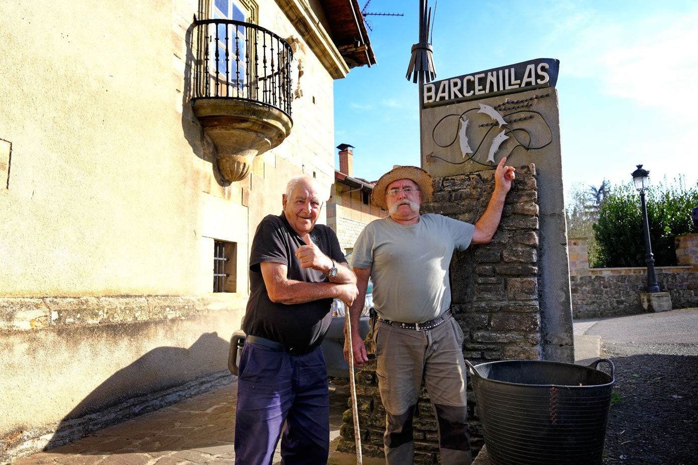 Dos vecinos muestra el cartel del pueblo orgullosos tras conocer el premio