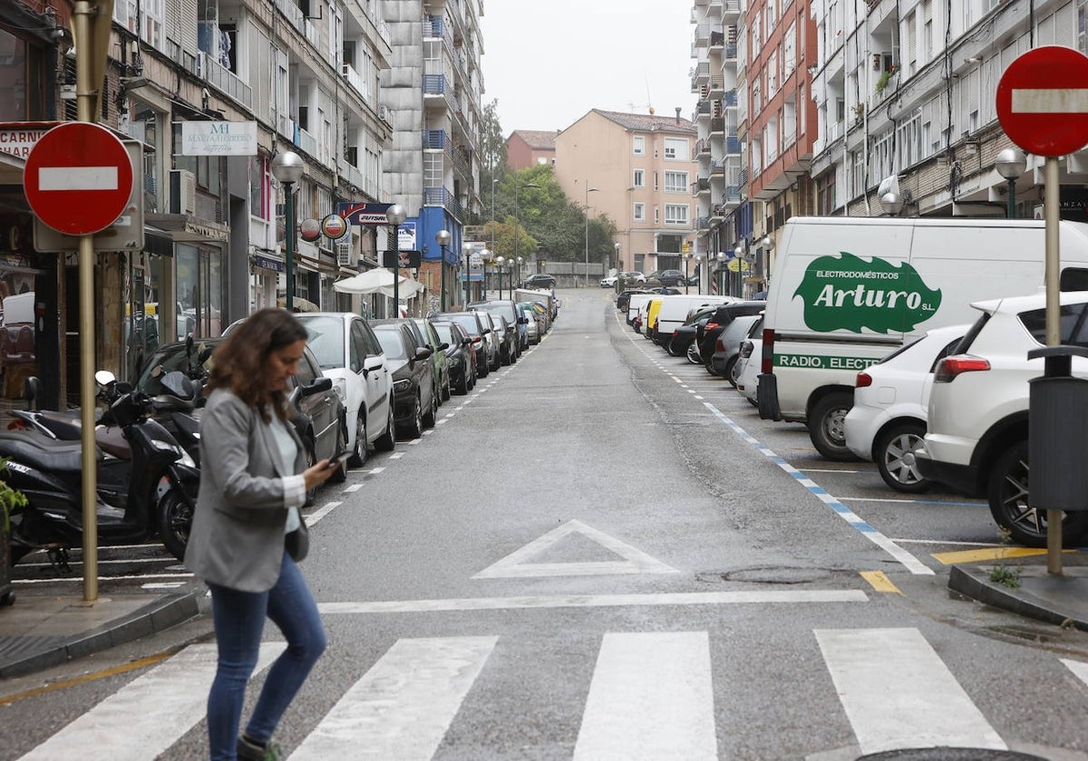 Una mujer cruza un paso de peatones, frente a la calle Félix Apellaniz de Torrelavega.