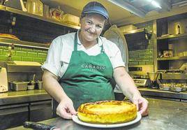 Una integrante del equipo de cocina muestra una tarta de queso recién hecha.