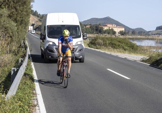 Una furgoneta circula detrás de un ciclista en la carretera de los puentes.