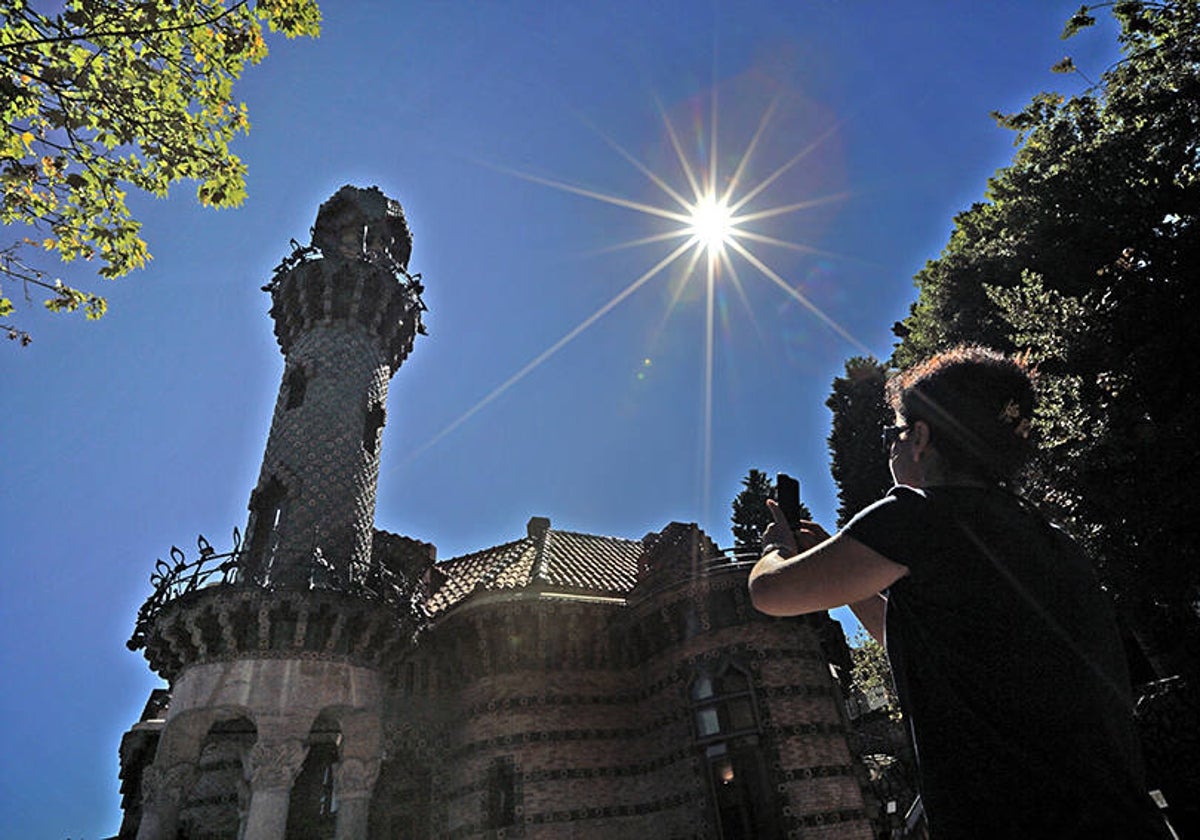 Una visitante fotografía el Capricho en un día soleado.