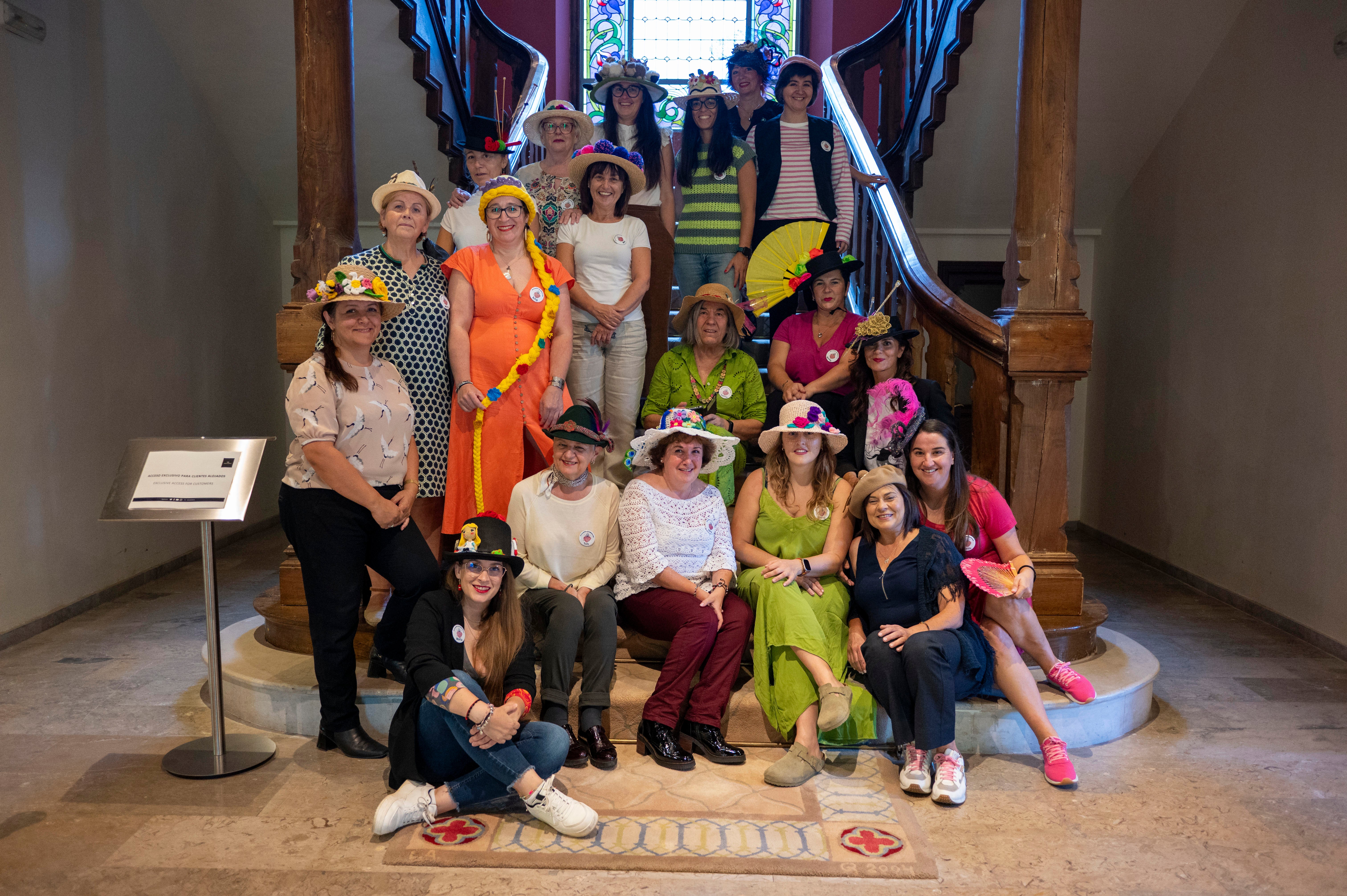 Foto de familia con algunas participantes mostrando los sombreros que han creado para la exposición que tuvo lugar.