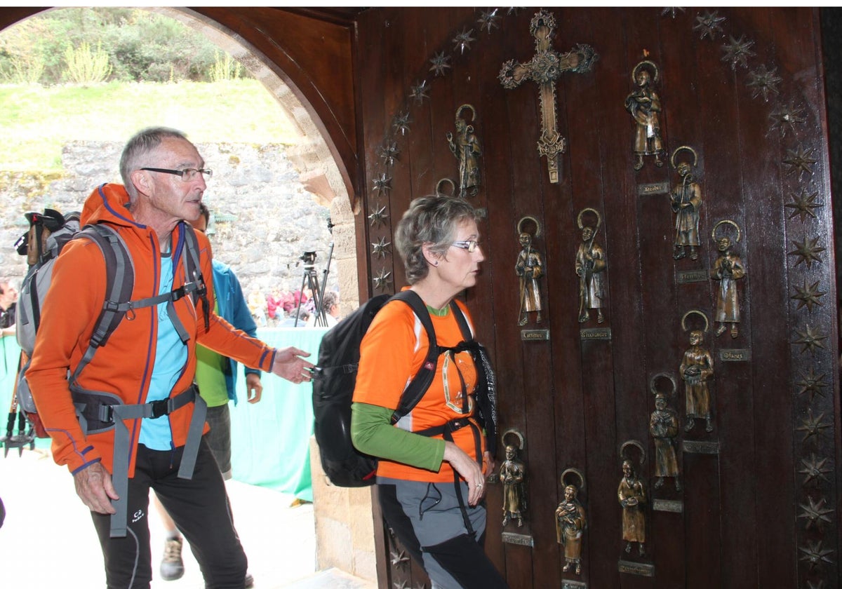 Dos peregrinos entran por la Puerta del Perdón del monasterio de Santo Toribio