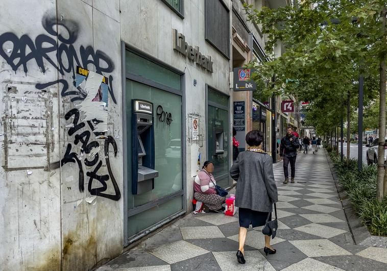 Un grafiti en la fachada de una sucursal de Liberbank cerrada preside un tramo de la calle Isabel II.