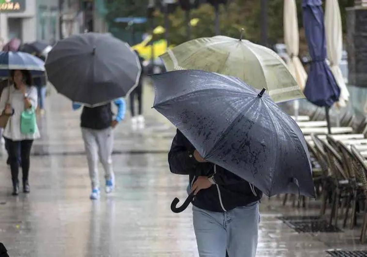 Paraguas bajos para evitar que los vuele el viento en el último temporal en Santander.