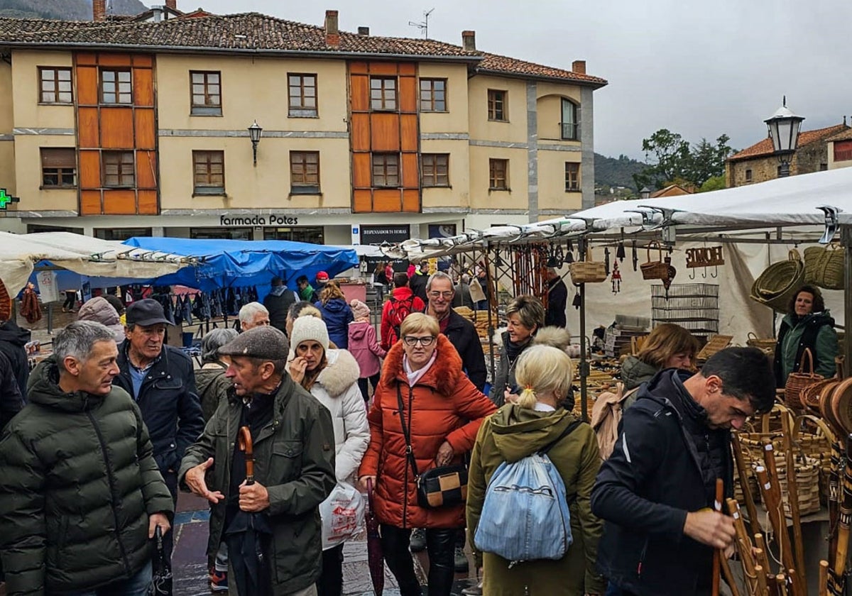 Varias personas hacen sus compras en el mercado, con el paraguas en la mano porque hubo rachas de lluvia durante la jornada.